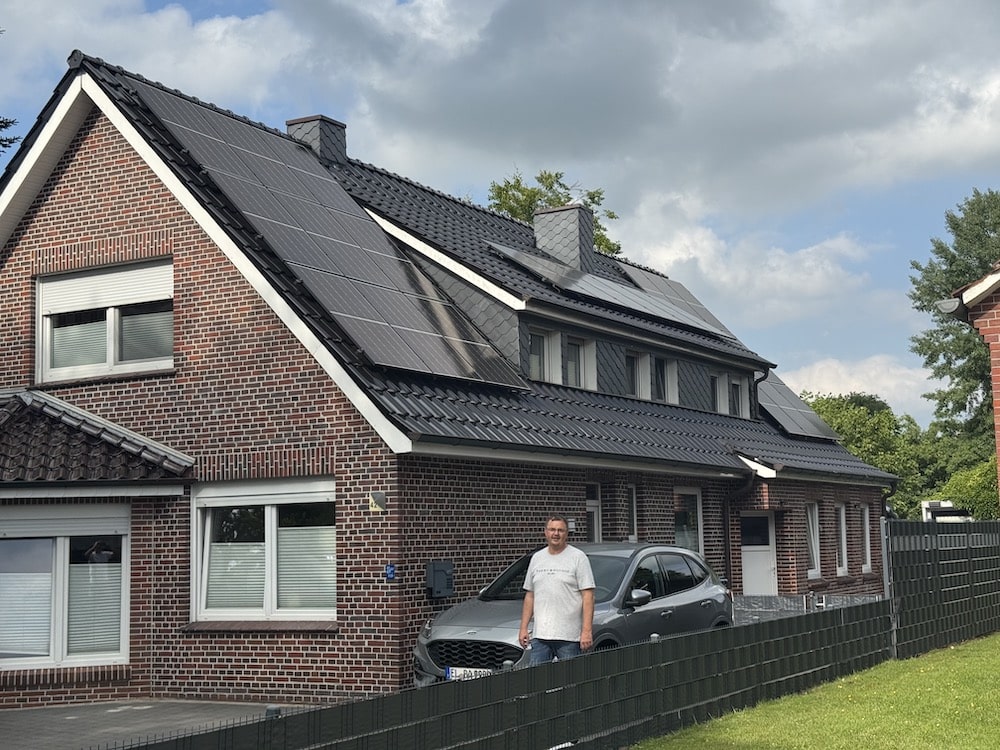 Paul Energie - Referenzbild des Kunden. Reiner Brinkmann steht vor seinem Haus auf welchem Solaranlagen montiert sind