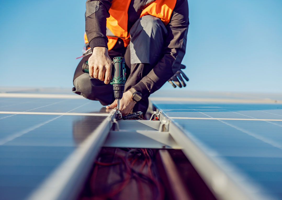 Nahaufnahme eines Handwerkers, der ein Solarpanel auf dem Dach fachgerecht installiert