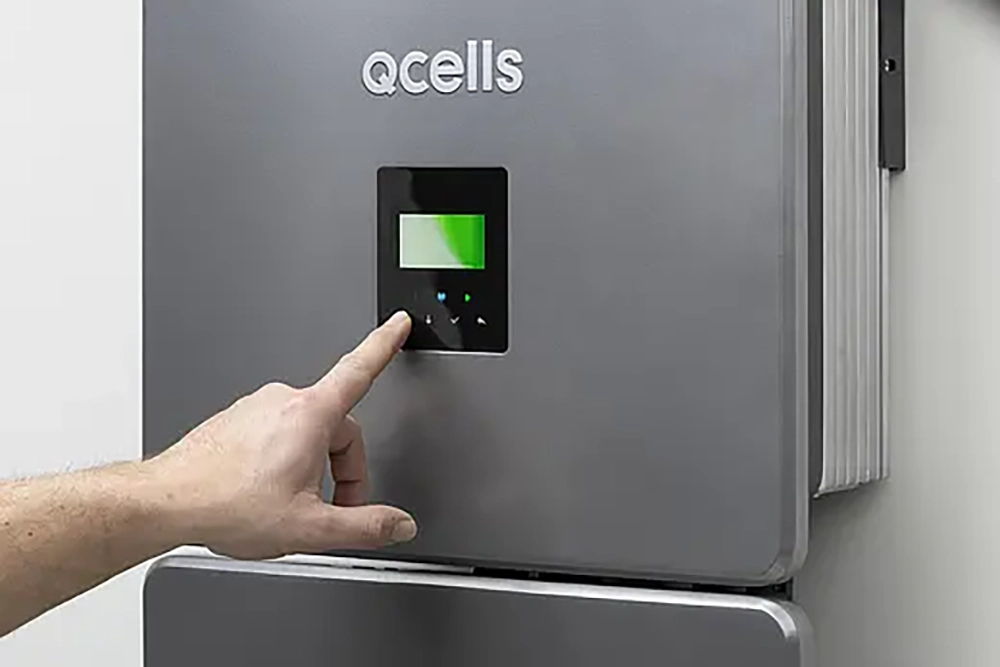Abbildung QCELLS Home Energiesystem an der Wand mit Hand die das Gerät bedient